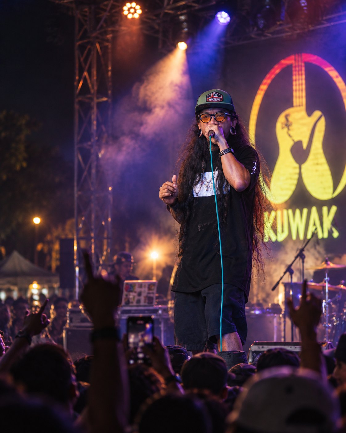 Love Blanca performing live on stage, singing into a mic above a crowd with raised hands